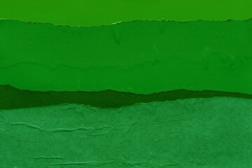 Green torn paper collage close-up. Texture made from various paper and cardboard parts. Damaged old...