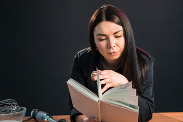 Excited female is going to cook something special, reading cookbook.