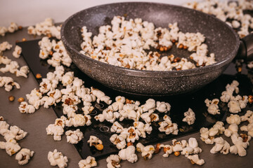 Making popcorn in a frying pan without a lid, popcorn scattered on the table, a mess in the kitchen, popcorn day