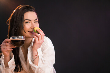Lovely young woman is drinking her morning coffee with macaroon.