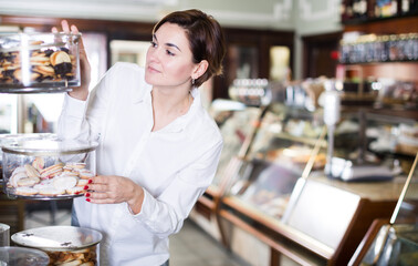 .Young female client choosing delicious dessert in confectionery.