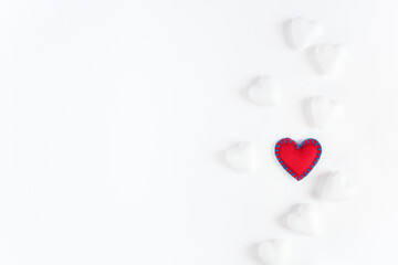 red heart made of fabric with blue edging on a white background surrounded by white dull hearts.
