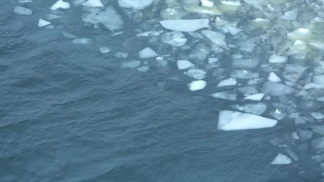 Ice floe floats in water, fragments of ice in the spring on the river, spring melting of ice, broken ice and waves. 