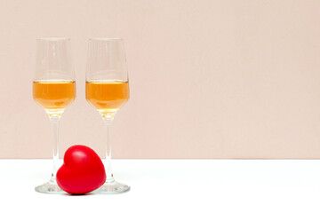 Two champagne glasses and red heart on pink background with copy space, valentines day, love, honeymoon concept