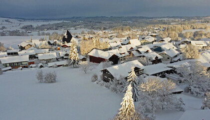 Luftaufnahme mit einer Drohne von einer kleinen Stadt in Bayern mit Schnee in der Abendsonne