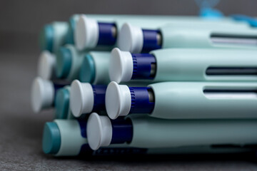 Bokeh and closeup of backends and fronts of syringe self application pens on rustic gray kitchen counter background. Studio medical equipment still life concept with auto-injector disposable devices. © Maarten Zeehandelaar