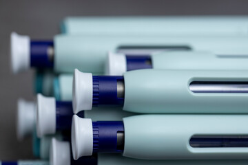 Macro closeup of syringe self application pens on rustic gray kitchen counter background. Studio medical equipment still life concept with auto-injector disposable devices.