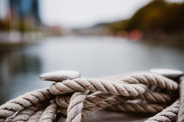 Fototapeta premium Cuerda blanca gorda en una barco navegando el rio de bilbao en españa con paisaje desenfocado.