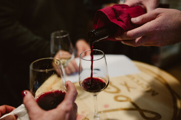 Manos echando vino tinto a tres copas  medio vacías