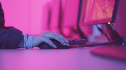 Female hand with long nails moves the mouse and prints text, play video games online. Dark room, evening, pink light. - Powered by Adobe