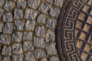 part of the road hatch with Greek ornament on the road made of granite stone