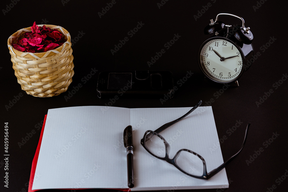 Aufkleber closeup of an opened notebook with a pen and eyeglasses on top next to a phone and alarm clock