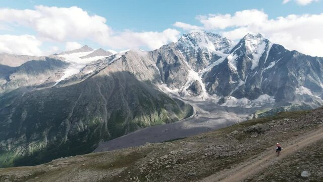 View from the hill top of endless snow capped mountain range. Clip. Breathtaking wild nature with clouds floating above huge mountains.