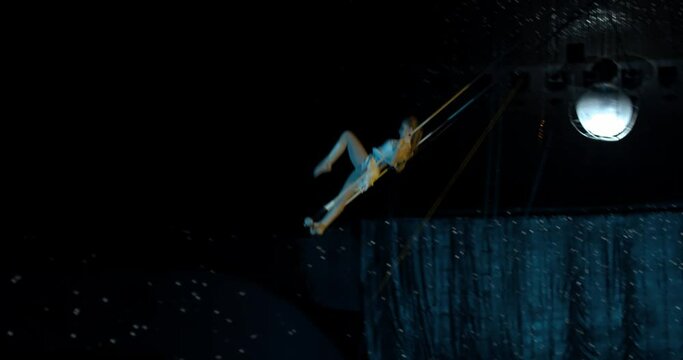 Aerial acrobat is doing dangerous tricks on a trapeze high in the air, 4k