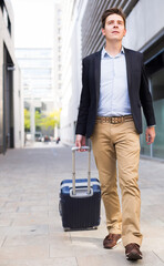 Portrait of cheerful male standing with bag at the modern street