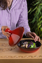 Girl opens the lid of the salad bowl with the prepared fresh vegetable salad