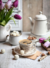 Cup of coffee with sugar cubs and coffee pot. Coffee cup, spring tulip flowers.
