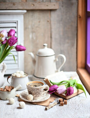 Cup of coffee with sugar cubs and coffee pot. Coffee cup, spring tulip flowers.