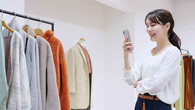 アパレルショップでスマホを使う女性
