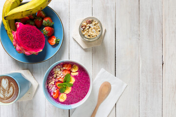 A fresh smoothie bowl made from banana, dragon fruit, milk and strawberries served in a bowl for a healthy nutritious breakfast