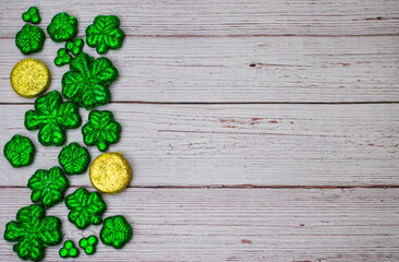 Glitter Four Leaf Clovers and Gold Coins on a White Wood Background