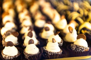 Small cakes in large quantities. Sweets with white mousse and chocolate.