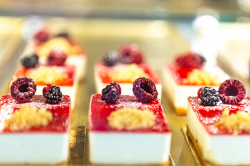 Small cakes in large quantities. White cakes with raspberries and blackberries.