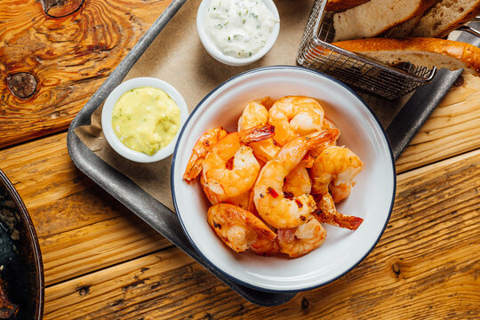 Top View Of A Bowl Of Shrimps With Bread Slices And Sauces On A Tray On The Table