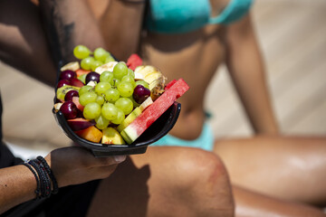 Selective focus shot of a young man holding a platter full of various fruits