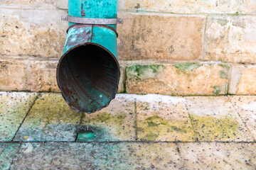 Storm water drain. Gutter from the roof. Water pours out of the gutter onto the rocks.