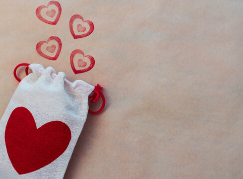 Saco de tela con un coraz&oacute;n grande y sellos de corazones rojos sobre papel marr&oacute;n. 