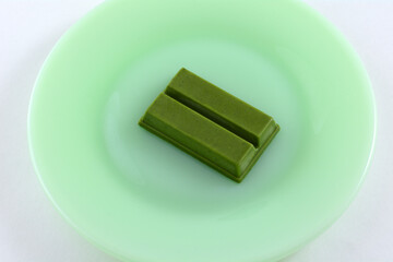 Dark green chocolate matcha flavored candy bar on green plate on white background