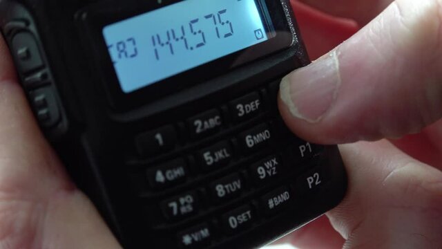 Handheld radio tuning into different frequencies and listening to broadcasts
