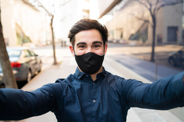 Portrait of young man taking a selfie outdoors.