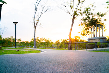 Obraz premium Asphalt walk and running pathway in green city park sunset