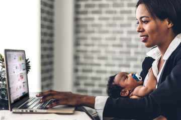 Portrait of african american black mother relaxing using technology of laptop computer with black baby while sitting on table.Young creative african girl working at home.work from home concept
