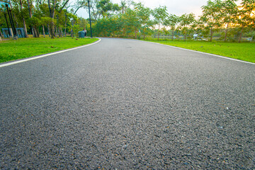 Asphalt walk and running pathway in green city park sunset