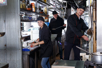Obraz premium Positive cooks in process of working in kitchen of restaurant
