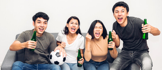 Group of asian friends drinking beer together and watching soccer game on sofa at home.Friendship...