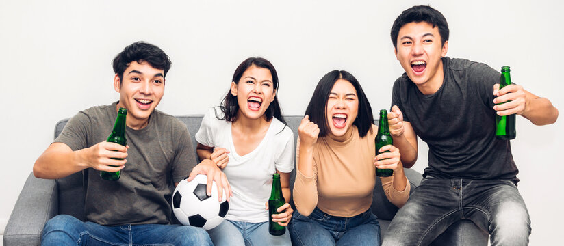 Group Of Asian Friends Drinking Beer Together And Watching Soccer Game On Sofa At Home.Friendship And Party Concept