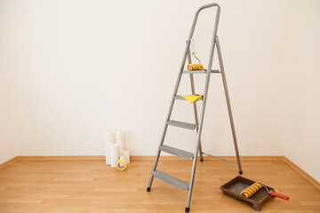 stepladder ready to work in the room. Wallpaper gluing in a room. Tools for gluing white wallpapers. White room after renovation. Fresh repair in a room