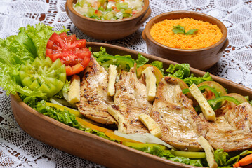 Sliced ​​chicken breast, grilled with rennet cheese and green salad served in clay bowl. Traditional Brazilian cuisine.