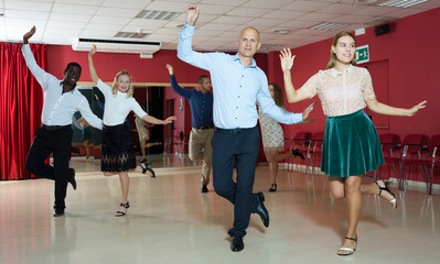 Smiling people learning tap dance movements in dancing class..