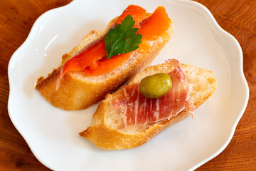 Canapes, salmon and sliced ham placed on baguette