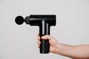 men's hands holds massage gun. medical-sports device helps to reduce muscle pain after training,...