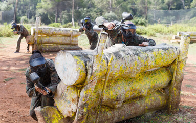 Fototapeta premium Portrait of positive man and woman paintball players in full gear playing outdoors