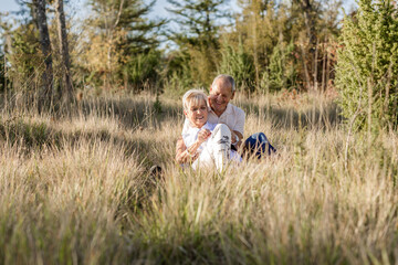 Naklejka na ściany i meble Senior couple in love and very happy enjoying a walk in the field at sunset