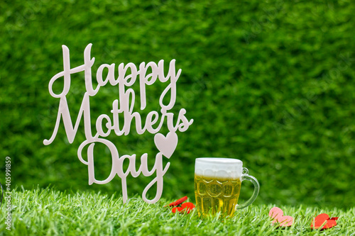 Happy Mother's Day with beer on green grass background