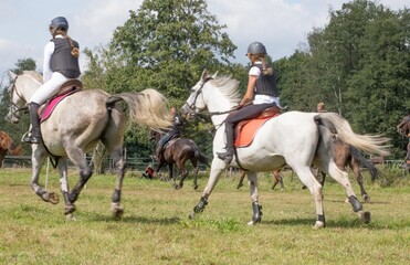 children gallop in protective vests in competitions equestrian girls