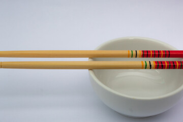 Chopsticks and a white and empty bowl.